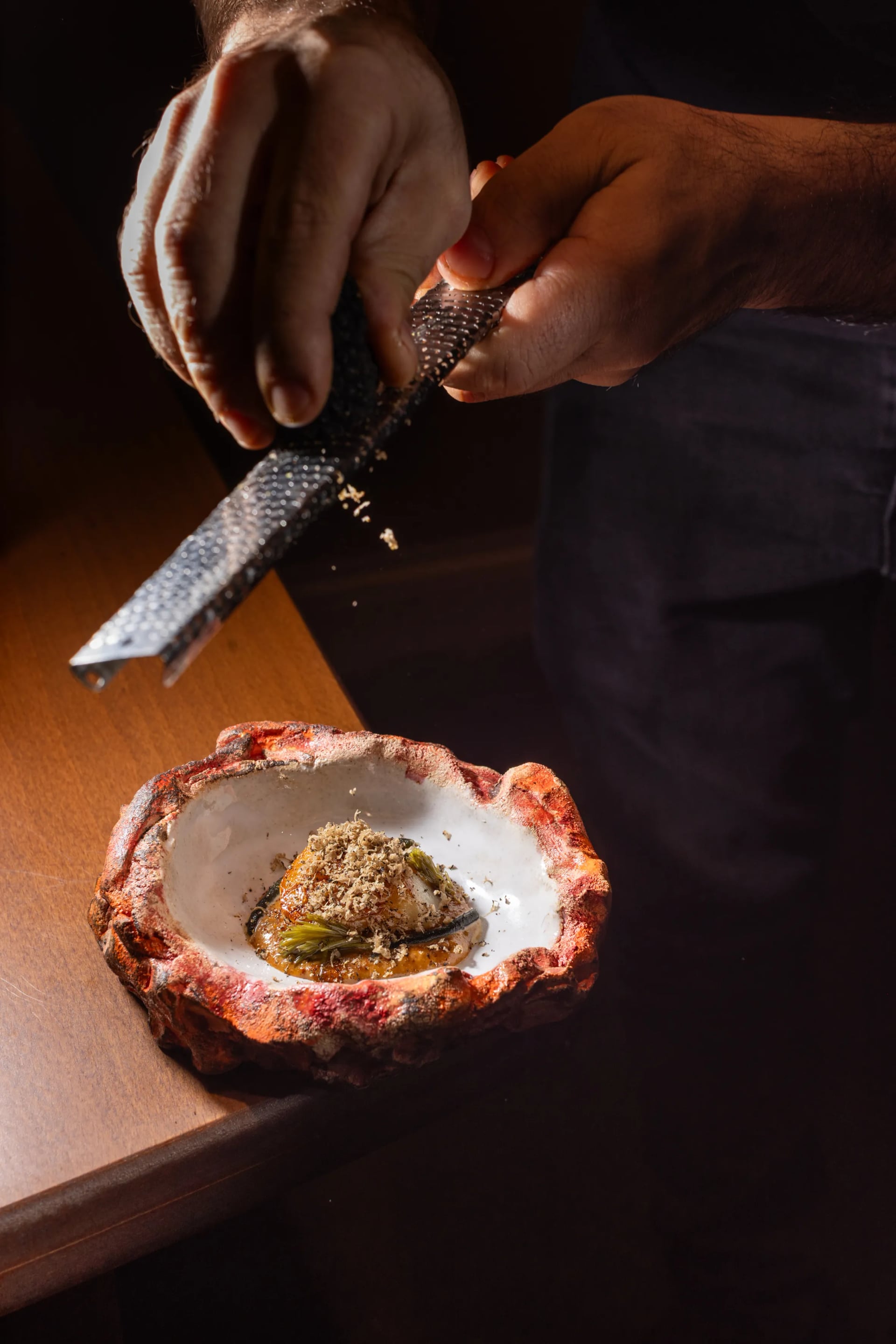 Chef Altin Mero grating fresh black truffle over a fine dining course at MERO restaurant Antwerp